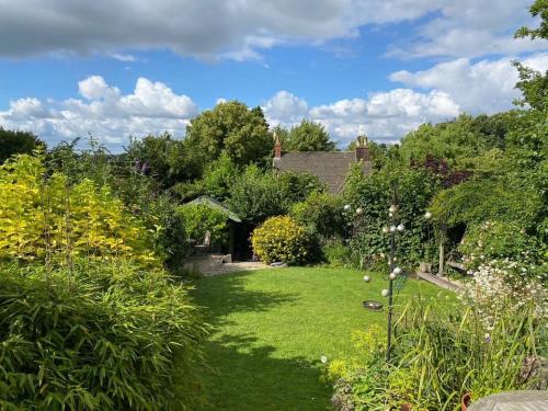 einen Garten mit üppigem grünen Gras und Büschen in der Unterkunft Sweet Modern Country Cottage with Garden in Frome