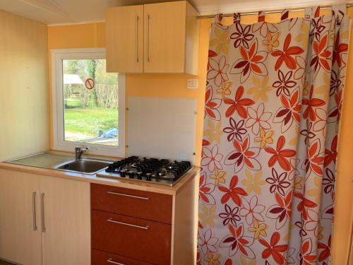 a kitchen with a stove and a sink and a window at Camping La Saline d'Arc et Senans in Arc-et-Senans
