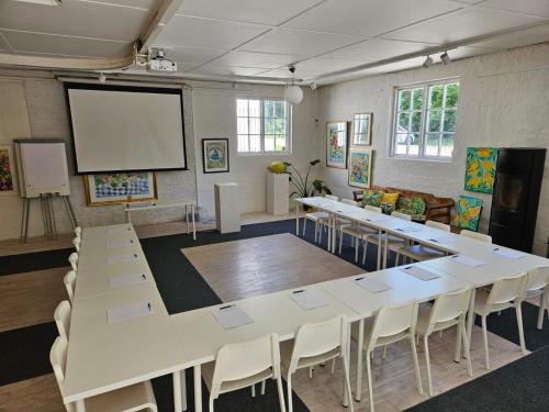 a conference room with a large white table and chairs at Kaptenshuset Hotell in Kivik