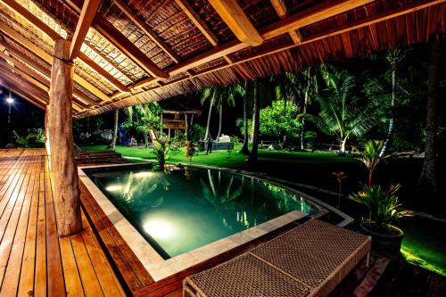 a swimming pool under a wooden pergola at Baha Baha Villa Sailo Mentawai in Katiet