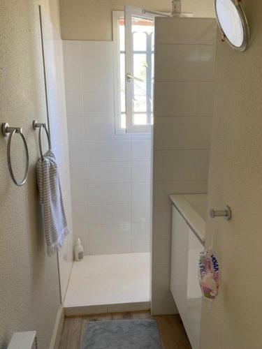 La salle de bains blanche est pourvue d'une douche et d'une fenêtre. dans l'établissement PCOGPETS Appartement avec belle vue Marina et piscine à Port-Cogolin, à Cogolin
