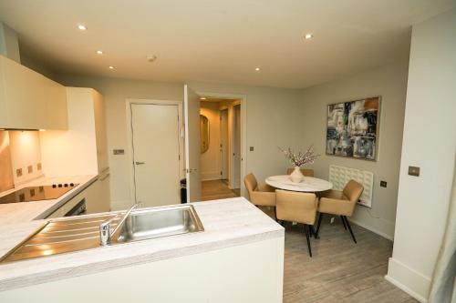 a kitchen and dining room with a sink and a table at NOVU Apartments Liverpool Waterfront in Liverpool