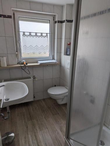 La salle de bains est pourvue de toilettes, d'un lavabo et d'une fenêtre. dans l'établissement Ferienwohnung Beck, à Ansbach