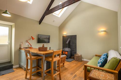 a living room with a table and a fireplace at Tranquil 1 bedroom cottage 15 mins drive to sea in Mydroilin