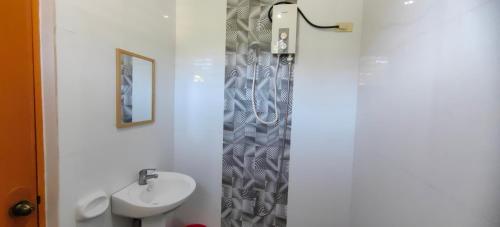 La salle de bains est pourvue d'un lavabo et d'un rideau de douche. dans l'établissement OYO 1065 Summer Wind Pension, à Puerto Princesa