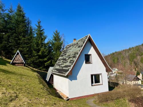 Urige Berghütte mit Kamin in Pobershau im Erzgebirge nahe Schwarzwassertal في Pobershau: منزل أبيض على سقف أسود على تلة