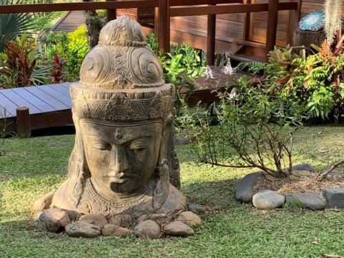 a stone statue of a head in a garden at Oasis de Tendéa - Bali à Farino in Farino