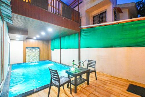uma piscina com mesa e cadeiras ao lado de uma casa em SK Villa em Āmbavna