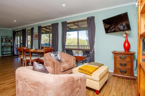 uma sala de estar com um sofá, uma cadeira e uma mesa em Pecan Hill BNB em Toodyay