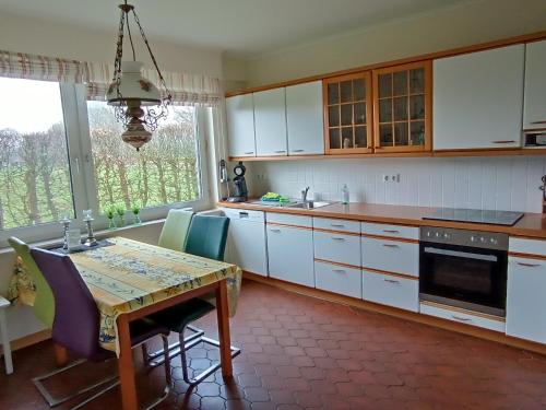 una cocina con armarios blancos y una mesa con sillas. en Ediths Haus, en Rhauderfehn