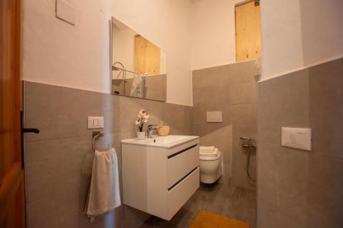 een badkamer met een wastafel, een toilet en een spiegel bij Villa Onda in Valledoria