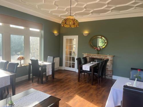 uma sala de jantar com mesas e cadeiras e um lustre em Heath Cottage Hotel em Dewsbury