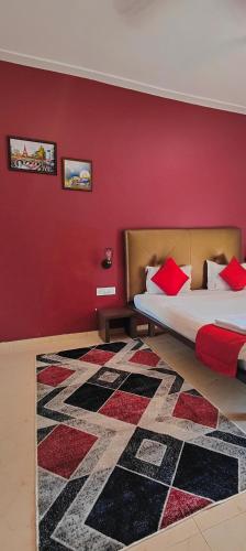a bedroom with two beds and a red wall at Rain Raga Resort in Mahabaleshwar