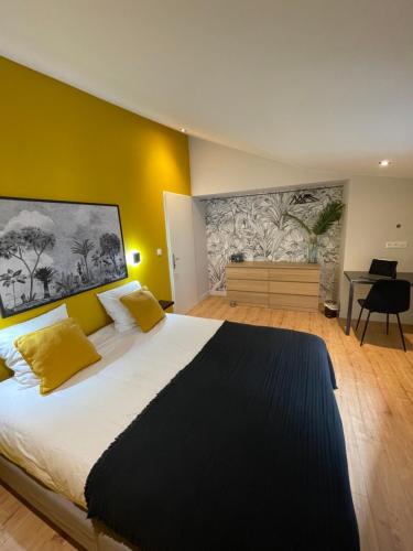 a bedroom with a large bed with yellow walls at L Original - TravelHome - Free wifi - 6 travelers in Villefranche-sur-Saône