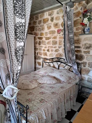 1 dormitorio con cama con dosel en una pared de piedra en locationseians var studio mimosa 2 etage, en Seillans