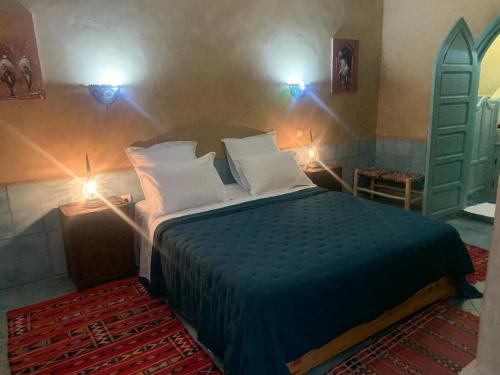 a bedroom with a bed with two lights on the wall at Hotel Riad Taroudant in Taroudant