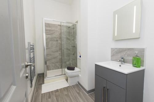 a bathroom with a shower and a toilet and a sink at K Suites - Oak Court in Brierley Hill