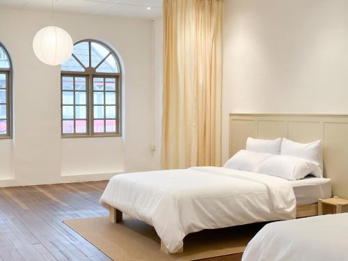 a white bedroom with two beds and a window at Heritage Vacation Inn old street view in Kuching