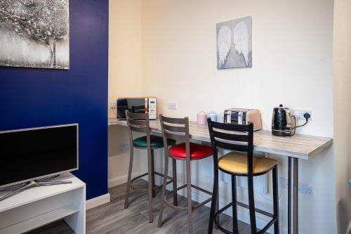 een bar met drie krukken in een kamer met een tv bij Station Apartment - 3 bedroom, five minutes from Harrogate Convention Centre in Harrogate