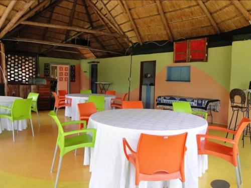 Habitación con mesa blanca y sillas coloridas. en Hippo Paradise Lodge and Campsites, en Kariba