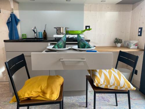 una cucina con due sedie e un tavolo con un cuscino giallo di Auf Wolke 7 - Gäste-Studio im Mini House in CH-4556 Aeschi SO a Aeschi