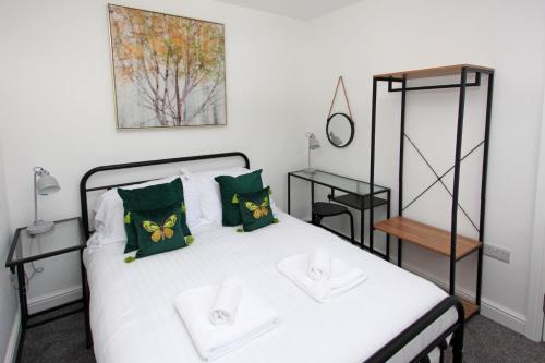 a bedroom with a white bed with green pillows at Hartshorne House in Telford