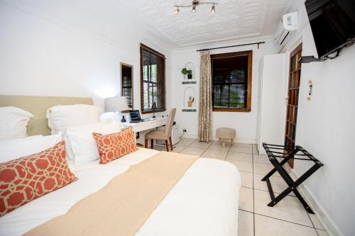 1 dormitorio con cama blanca y escritorio en 84 on Fourth Guest House en Johannesburgo