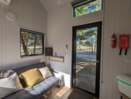 a living room with a couch and a sliding glass door at M13 Tiny House at Grampians Edge in Dadswells Bridge
