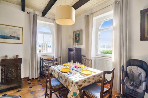 une salle à manger avec une table et des chaises et deux fenêtres dans l'établissement Adresse d'exception sur l'île Queffen - Loctudy, à Loctudy
