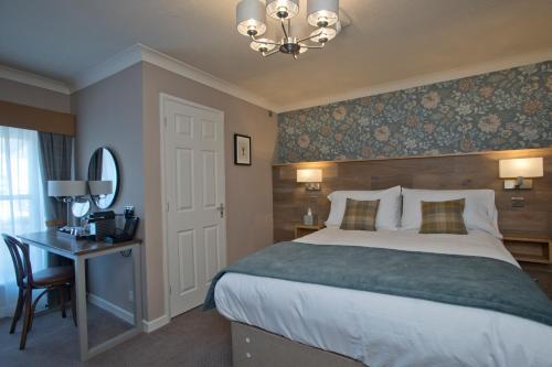 a bedroom with a bed and a desk and a mirror at The Lobster in Sheringham