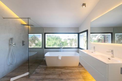 a bathroom with a tub and two sinks and a shower at Casa Guindilla in Portals Nous