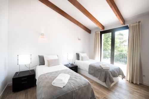 a bedroom with two beds and a window at Casa Guindilla in Portals Nous