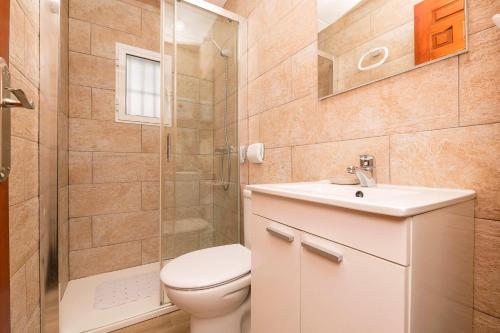 een badkamer met een toilet, een douche en een wastafel bij El Paseo del Faro in Chipiona