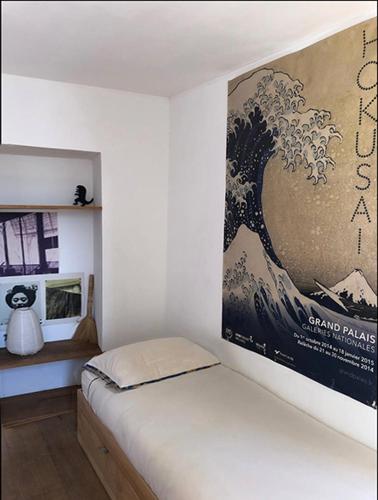 - une chambre avec une affiche d'une vague sur le mur dans l'établissement Superbe appartement au coeur de Montmartre, à Paris