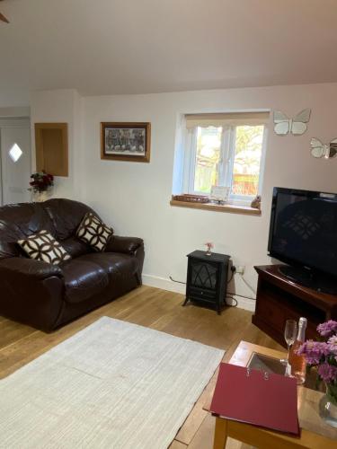 a living room with a leather couch and a television at 2 bedroom Holiday home in Norfolk private field in Wisbech