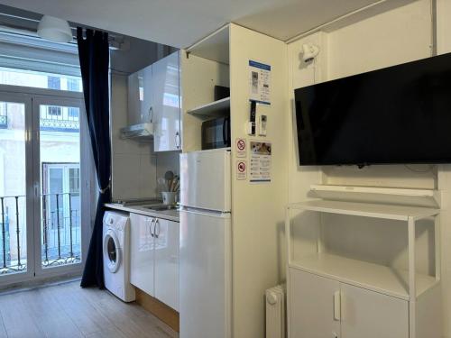 eine Küche mit einem Kühlschrank und einem TV an der Wand in der Unterkunft Apartamento con encanto en el corazón de Chueca, Madrid in Madrid