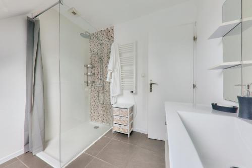 une salle de bain blanche avec une douche et un lavabo dans l'établissement Maison pour 6 - Jardin - Proche plage, à Sarzeau