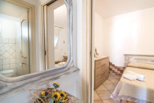 baño con espejo, cama y lavamanos en Le Lantane 2, en Irgoli