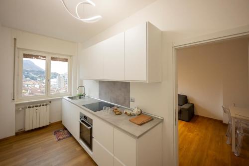 uma cozinha com armários brancos e uma grande janela em Le Case Di Ferdinando em Lecco