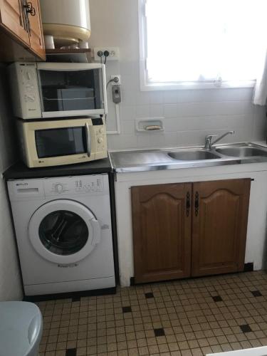 une cuisine avec un micro-ondes et un lave-linge dans l'établissement T2 au calme, plage à 100 m, parking privé, WIFI, clim, à Canet