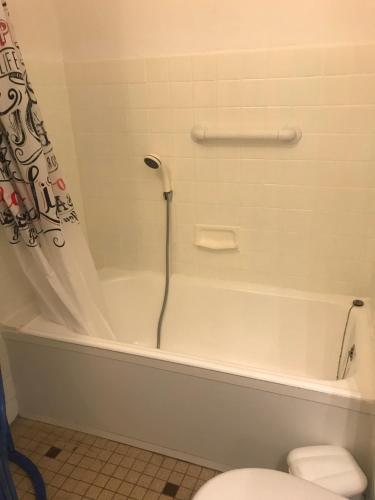 une salle de bain avec une baignoire blanche et des toilettes dans l'établissement T2 au calme, plage à 100 m, parking privé, WIFI, clim, à Canet