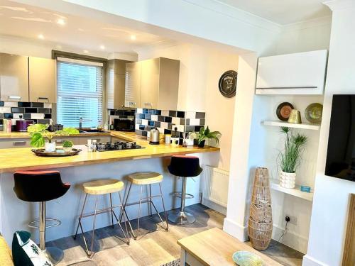 a kitchen with a counter and bar stools in it at Modernised cottage Sleeps Six in Ore