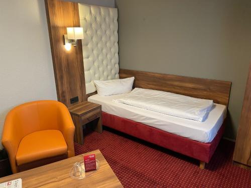 バート・ヴェーリスホーフェンにあるMorada Hotel Bad Wörishofenのベッドと椅子付きの小さな部屋です。