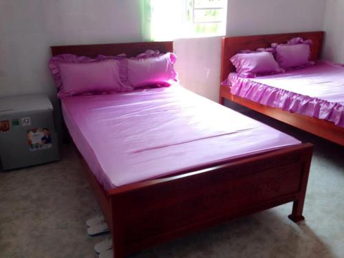 Habitación con 2 camas individuales y sábanas rosas. en NHÀ NGHỈ KIM ÁNH KIM, en Trà Vinh