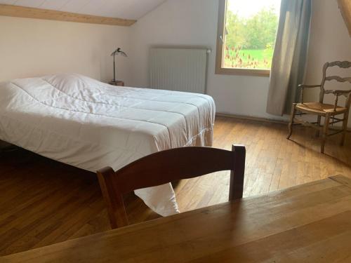 a bedroom with a bed and a chair and a window at séjour nature au Shed - Sornay - Haute Saône 