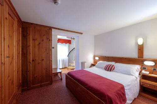 a bedroom with a large bed with a red blanket at Hotel Miramonti Corvara in Corvara in Badia