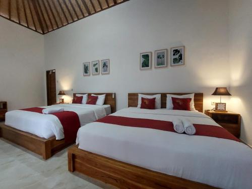 two beds with red and white sheets in a bedroom at Innora Jungle Resort And Spa in Nusa Penida