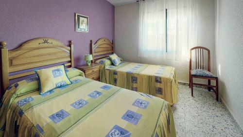 a bedroom with two beds and a chair at Casa Rural el Guarda in Madrid