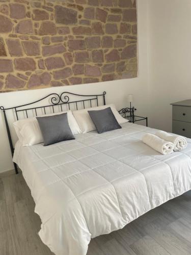 una camera da letto con un grande letto bianco e un muro in pietra di CIVICO 16 a Carloforte