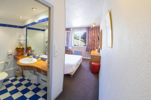 uma casa de banho com uma cama, um lavatório e um espelho. em Cit'Hotel Avantici Gap em Gap